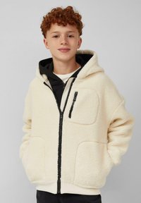 Cremiger Fleece-Reißverschluss-Hoodie mit schwarzen Akzenten, ausgestattet mit hohem Kragen, Fronttaschen und weichem Material. Die innere Schicht ist schwarz.