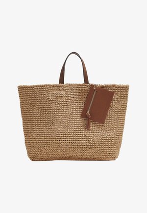 Geweven stro tas met bruine leren handvatten en een bevestigde bruine leren ritszak op een witte achtergrond.