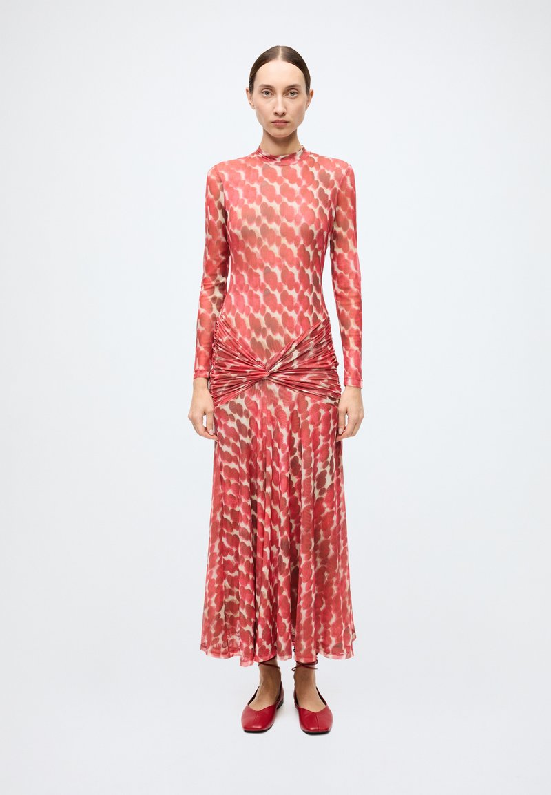 Robe rouge à manches longues avec une jupe fluide, présentant un motif texturé en nuances plus claires, des détails froncés à la taille et un tissu lisse.