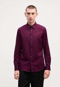 Langermet skjorte i dyp lilla, laget av glatt stoff. Har klassisk krage, knapplukking og subtilt merke logo på brystet.