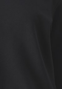 Felpa nera in cotone con una texture morbida e una finitura liscia, con collo a giro e cuciture a costine. Senza loghi o motivi visibili.
