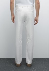 Witte op maat gemaakte broek met een rechte pijp, met een gladde textuur, achterzakken en een nette tailleband.