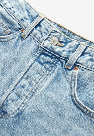 Jeans de mezclilla azul claro con textura desgastada, corte recto y detalles de costura visibles. Cuenta con un botón de metal y pasadores para cinturón.