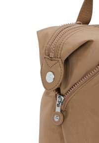 Bolsa de tela marrón con una superficie texturizada, que presenta un cierre con cremallera, acentos de cuero y un detalle del logotipo de la marca en metal.