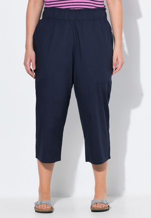 Pantalons cropped bleu marine en tissu léger et doux, avec une taille élastique et des poches latérales, offrant une coupe décontractée.