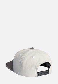 Gorra con un cuerpo de algodón gris claro y una visera de ante gris oscuro. Presenta orificios de ventilación blancos y una correa ajustable negra en la parte posterior.