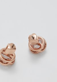 Roosakuldne kõrvarõngas, millel on ümmargune disain, selged gemstone aktsendid ja tekstureeritud viimistlus südamekujuliste külgekinnitustega.