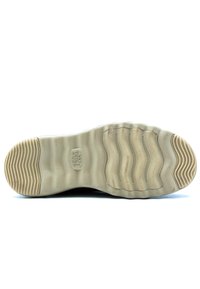 Semelle de chaussure en matériau en caoutchouc beige, présentant une texture ondulée, des motifs circulaires et le logo de la marque. Rainurée pour l'adhérence.