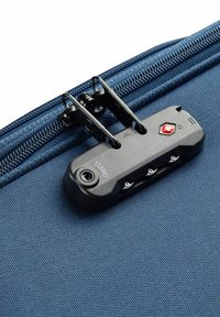 Tessuto della valigia blu scuro con una superficie tessurizzata. Presenta un meccanismo di chiusura nero con tre manopole e un emblema rosso per la sicurezza.