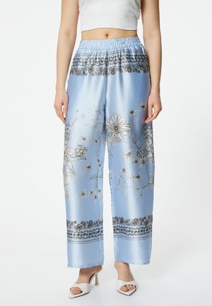 Light blue satin wide-leg pants with floral prints and a black decorative band at the hem. Features an elastic waistband for comfort.