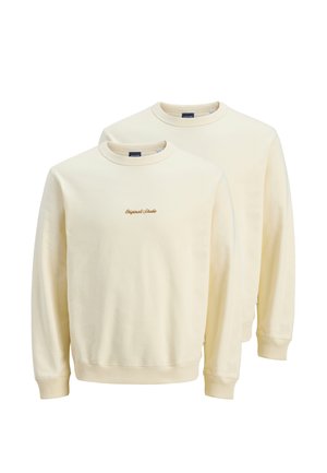 Sweatshirts crème à col ras du cou en tissu doux, avec des poignets et un ourlet côtelés, ornés de "Original Studio" brodé en marron sur la poitrine.