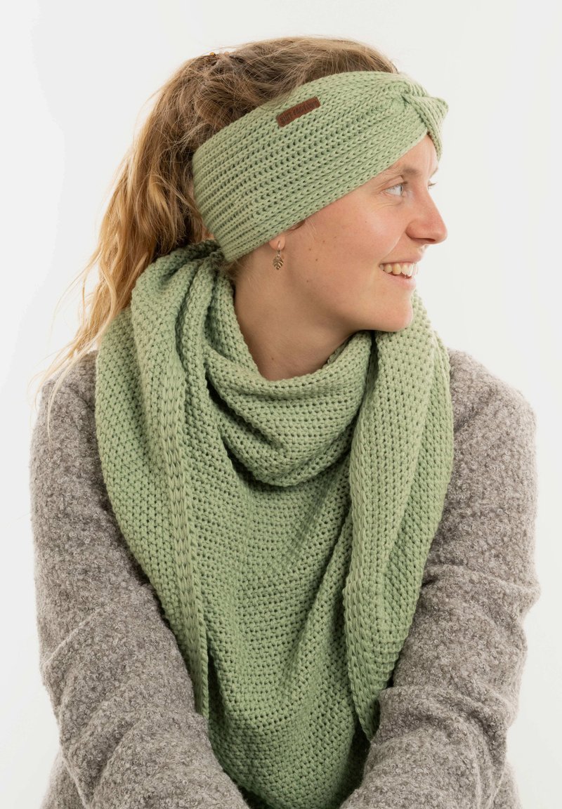 Fascia e sciarpa abbinata di colore verde chiaro realizzate a maglia, con un motivo testurizzato. La sciarpa si adagia comodamente attorno al collo.