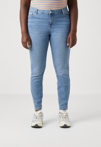 Light blue skinny jeans with a high waist, made of denim. Features front pockets and a subtle faded texture. Worn with grey and yellow sneakers.