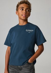 Tamsiai mėlyna medvilninė marškinėliai trumpomis rankovėmis su baltu "ALLSAINTS" logotipu ir azijietiškais simboliais priekyje. Apvalus iškirpimas, laisvas siluetas.