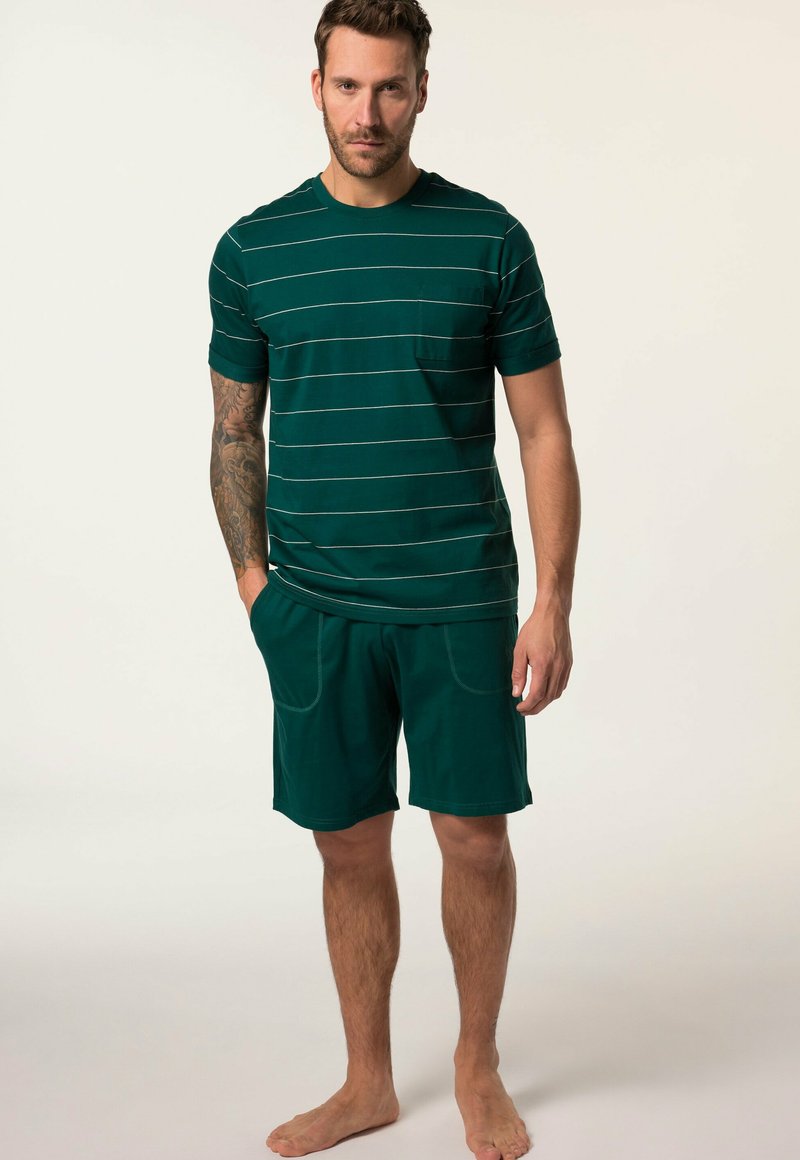 Camiseta verde de manga corta con rayas blancas y un bolsillo, combinada con pantalones cortos a juego que presentan una textura suave y detalles de costura.