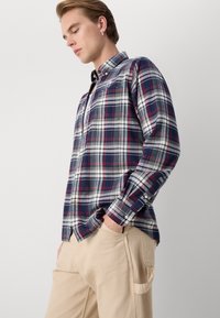 Gestreiftes Baumwollhemd in Marineblau, Rot und Weiß. Verfügt über einen Button-Down-Kragen, lange Ärmel und eine einzelne Brusttasche. Strukturierter Stoff.