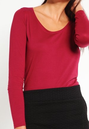 Haut à manches longues bordeaux avec un décolleté en U, fabriqué en tissu doux. Conçu avec une silhouette ajustée et une jupe noire texturée.