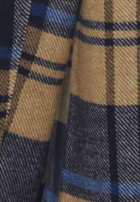 Tessuto in lana caratterizzato da un motivo a quadri marrone e blu navy con accenti blu e neri. La texture è morbida e calda, adatta per capi di abbigliamento esterni.