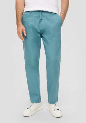 Pantalons en lin bleu clair avec une coupe décontractée, poches latérales et taille à cordon, associés à des baskets blanches.