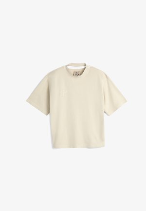 Cremefarbene Kurzarm-T-Shirt aus weichem Stoff, mit einem dezenten gestickten Design auf der linken Brust und einem Rundhalsausschnitt.