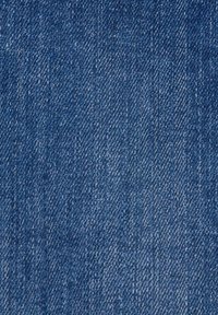 Gros plan de la texture d’un tissu denim bleu avec un tissage diagonal visible et des nuances variées de fils bleus et blancs.