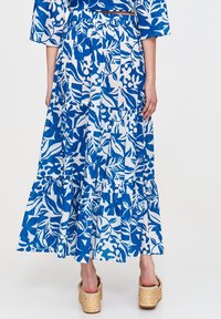 Flowy blue and white tiered skirt featuring a leaf pattern, made from lightweight fabric, with an elastic waistband and a long length.