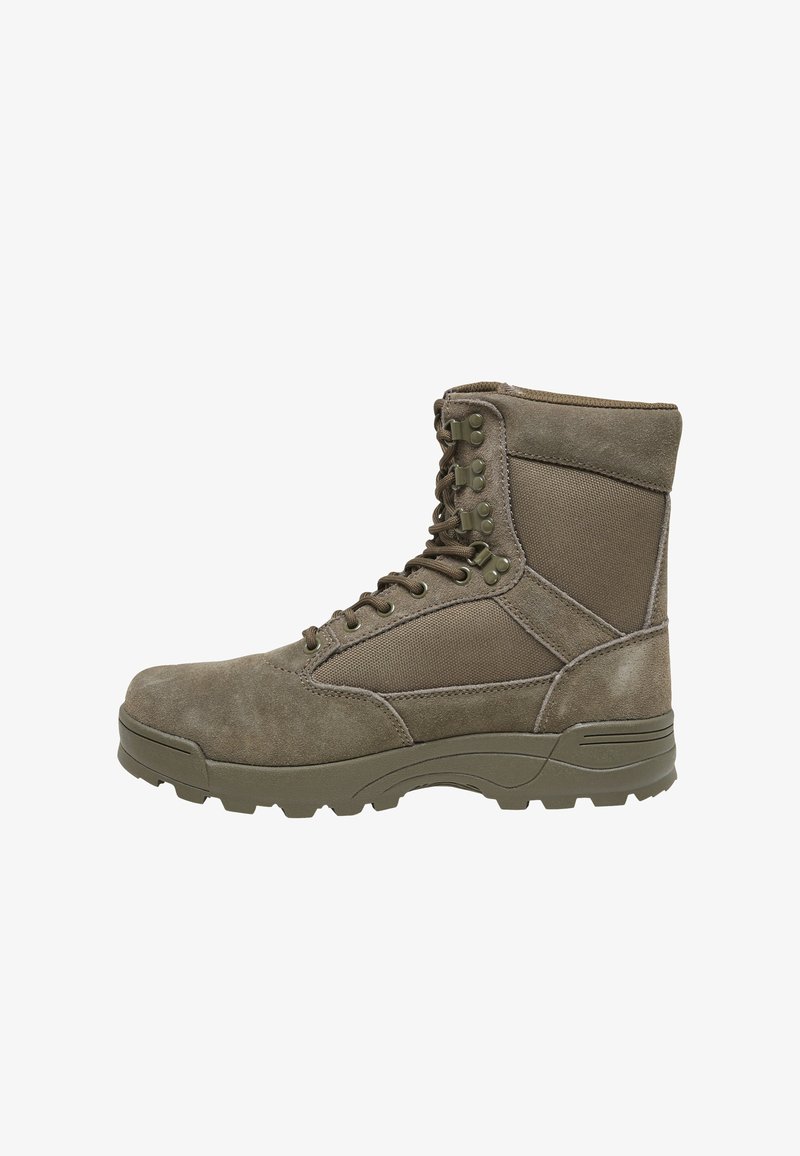 Bota de estilo militar en verde oliva oscuro, con parte superior de ante, puntera reforzada, paneles texturizados y suela de goma robusta con agarres.