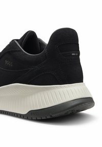Baskets en daim noir avec une semelle intermédiaire blanche texturée, une semelle extérieure noire et un discret marquage "BOSS" au talon et sur le côté.