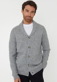 Grauer Strickcardigan mit Schalkragen, der ein strukturiertes Muster aufweist und sechs Knöpfe vorne hat. Lange Ärmel mit gerippten Bündchen.