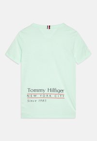Mátově zelené bavlněné tričko s krátkým rukávem, véčkovým výstřihem a potiskem loga s nápisem 'Tommy Hilfiger' a 'New York City' na zádech.