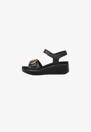 Sandale compensée noire avec bride à la cheville, bout ouvert et boucle circulaire décorative marron sur la bride avant.