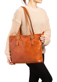 Borsa tote in pelle marrone con due spallacci e hardware in metallo. Texture liscia, forma rettangolare e dettagli di cucitura a contrasto.