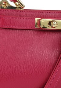 Roze leren handtas met een gestructureerde afwerking, voorzien van een gouden metalen sluiting en stikselaccenten langs de randen.