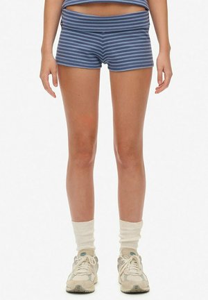 Shorts rayés bleus en tissu doux, dotés d'une taille élastique. Accentués par des chaussettes de sport blanches et des baskets de couleur claire.