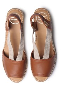 Sandali in pelle marrone con cinghie elastiche beige. Design aperto alla punta con dettagli cuciti sui bordi e suola texture.