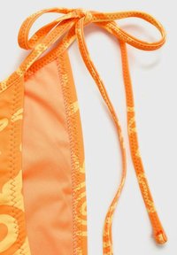 Oranžni bikini zgornji del s povezovanjem na vratu, gladko teksturo in subtilnim vzorcem na tkanini. Robovi so šivani v kontrastni barvi.