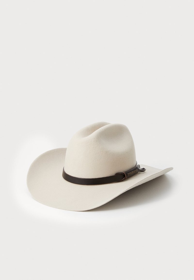 Valge villane cowboy müts laia äärtega, pruuni nahkpaela ja metallist aktsendiga. Sile tekstuur, ümar kroon kahe lohkuva kohaga.