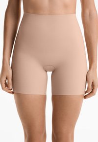 Beżowe szorty korygujące o wysokim stanie, wykonane z gładkiego, elastycznego materiału, z bezszwowym wykończeniem i małym otworem w kroku.