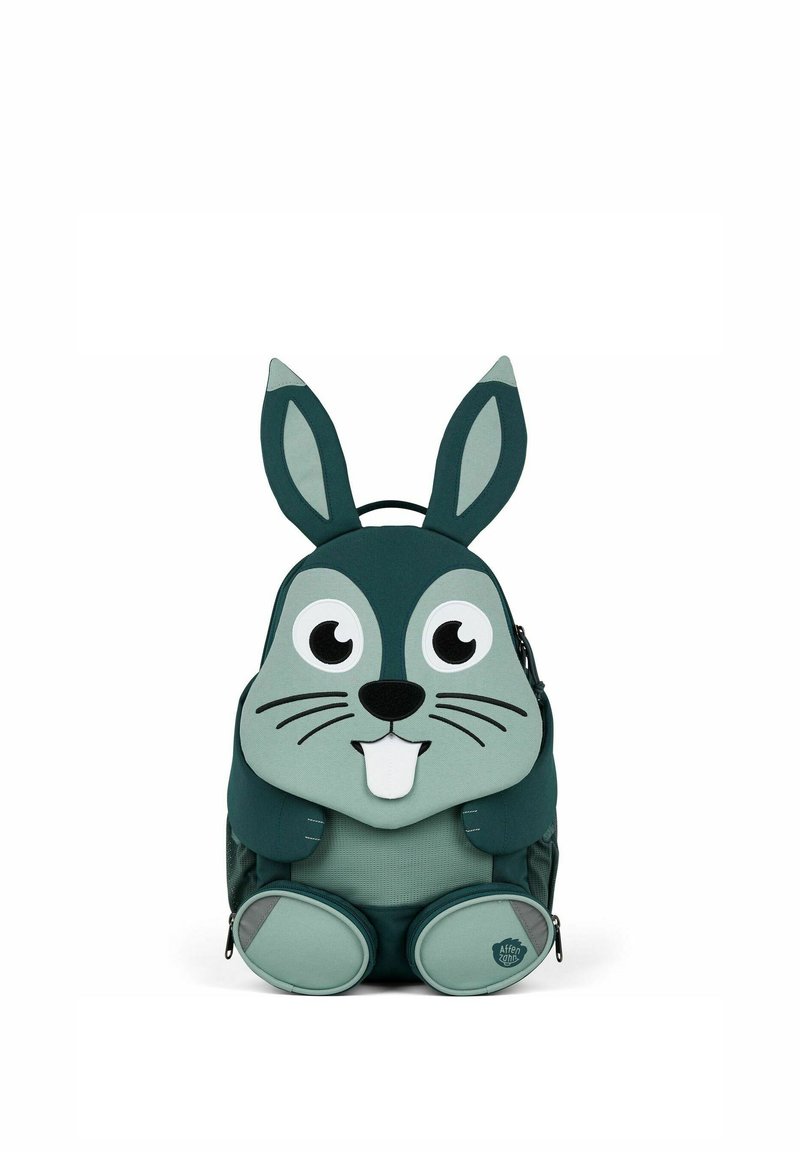 Grüner Stoffrucksack, der wie ein Hase gestaltet ist, mit langen Ohren, großen Augen, einer Schnauze und runden Füßen; enthält Reißverschlüsse und einen Griff.