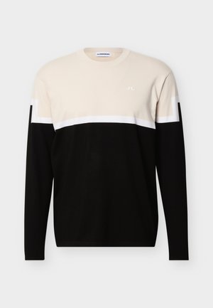 Sweter z długim rękawem z beżową górną częścią, białym paskiem i czarną dolną częścią, z małym białym logo na piersi.