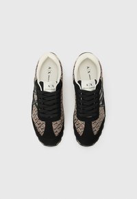 Black and tan sneakers with a geometric pattern, featuring a black suede upper, black laces, and a white cushioned sole.