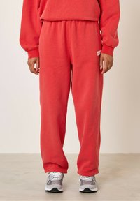 Punased puuvillased dressipüksid, millel on elastne vöökoht, küljetaskud ja mugav lõige. Külje peal on väike valge logo.