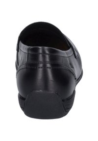 Zapato negro de cuero tipo mocasín con una textura suave, parte trasera redondeada y suela de goma con líneas de agarre sutiles a lo largo del talón.