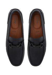 Mocasines de cuero negro con un acabado texturizado, que presentan un detalle de hebilla negra, plantillas marrones y costuras en contraste.