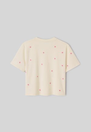 T-shirt crème à manches courtes avec de petits motifs brodés roses en forme d'étoiles éparpillés dans le dos sur un fond gris uni.