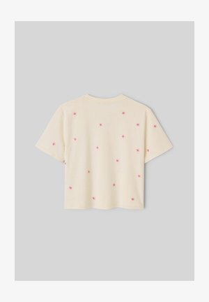 T-shirt crème à manches courtes avec de petits motifs brodés roses en forme d'étoiles éparpillés dans le dos sur un fond gris uni.
