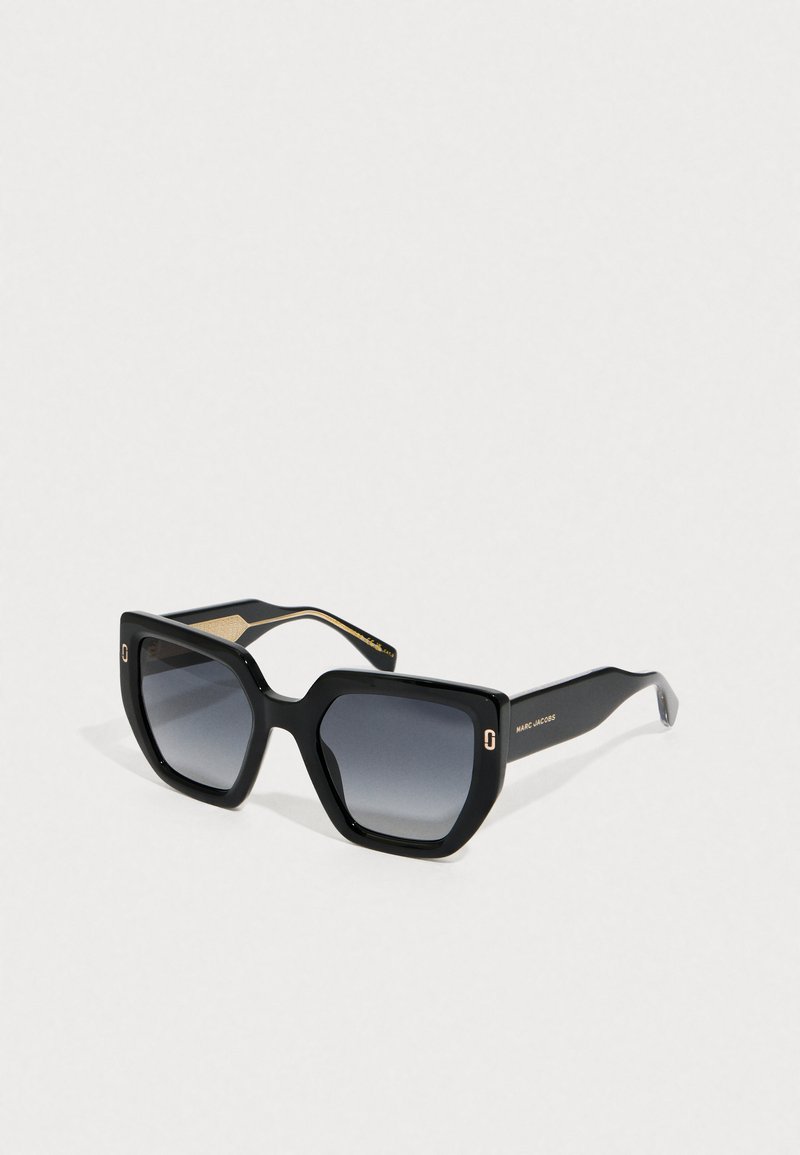 Gafas de sol cuadradas oversized de color negro brillante con lentes oscuros degradados y logotipo dorado de Marc Jacobs en las patillas.