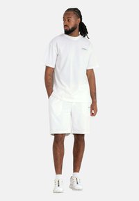 Witte katoenen t-shirt met een ronde halslijn en korte mouwen, gecombineerd met bijpassende witte shorts. Ook voorzien van logo-accenten en casual sneakers.