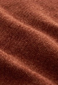 Brauner, strukturierter Stoff mit einer weichen, flauschigen Oberfläche, die einen reichen Farbton und subtile visuelle Variationen in Webart und Tiefe zeigt.