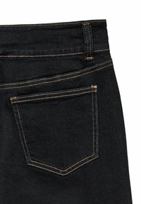 Črne denim hlače imajo en sam zadnji žep, kontrastno rumeno šivanje in gladko teksturo, kar prikazuje klasičen dizajn.